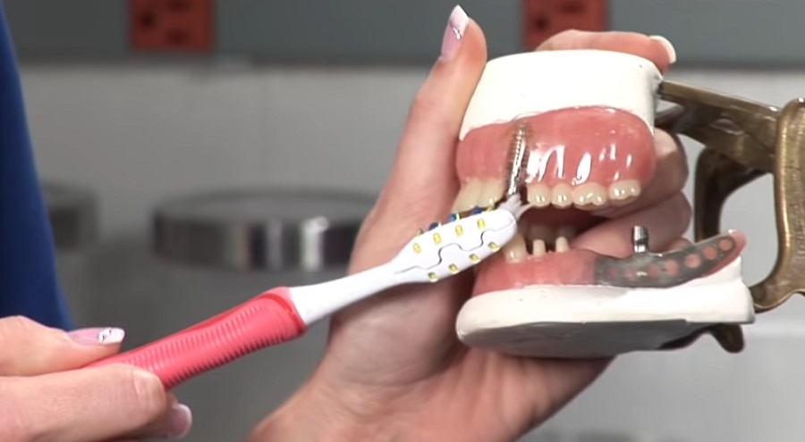 Dentálhigiénikus a helyes fogpótlás-tisztítást mutatja